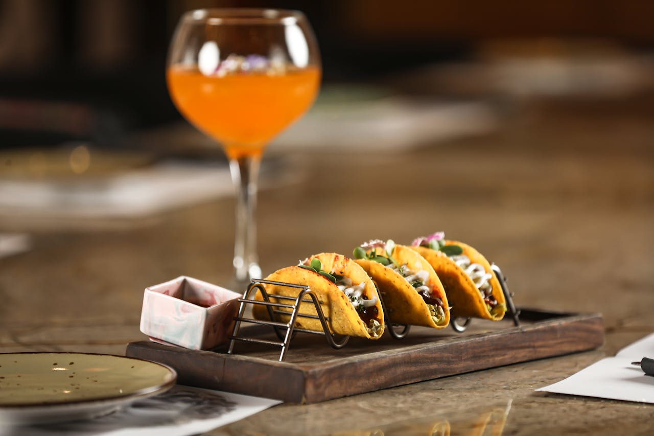Gourmet tacos displayed with a vibrant orange cocktail in a stylish Bengaluru restaurant.
