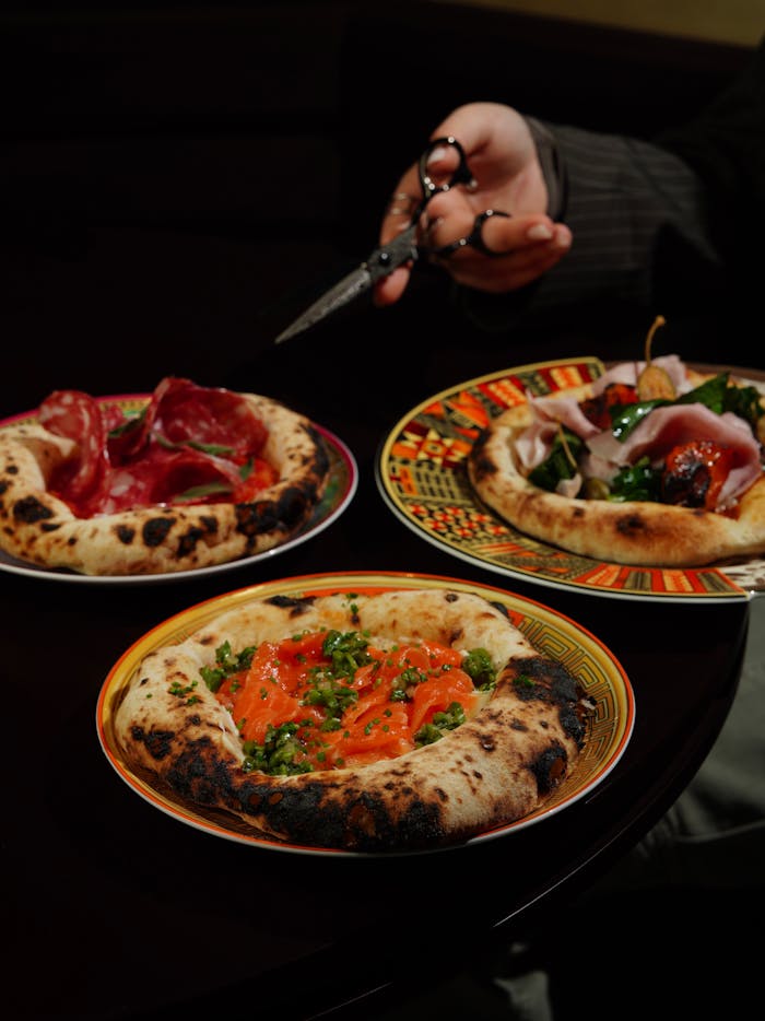 Delicious variety of pizzas presented stylishly on colorful plates. Perfect for food lovers.